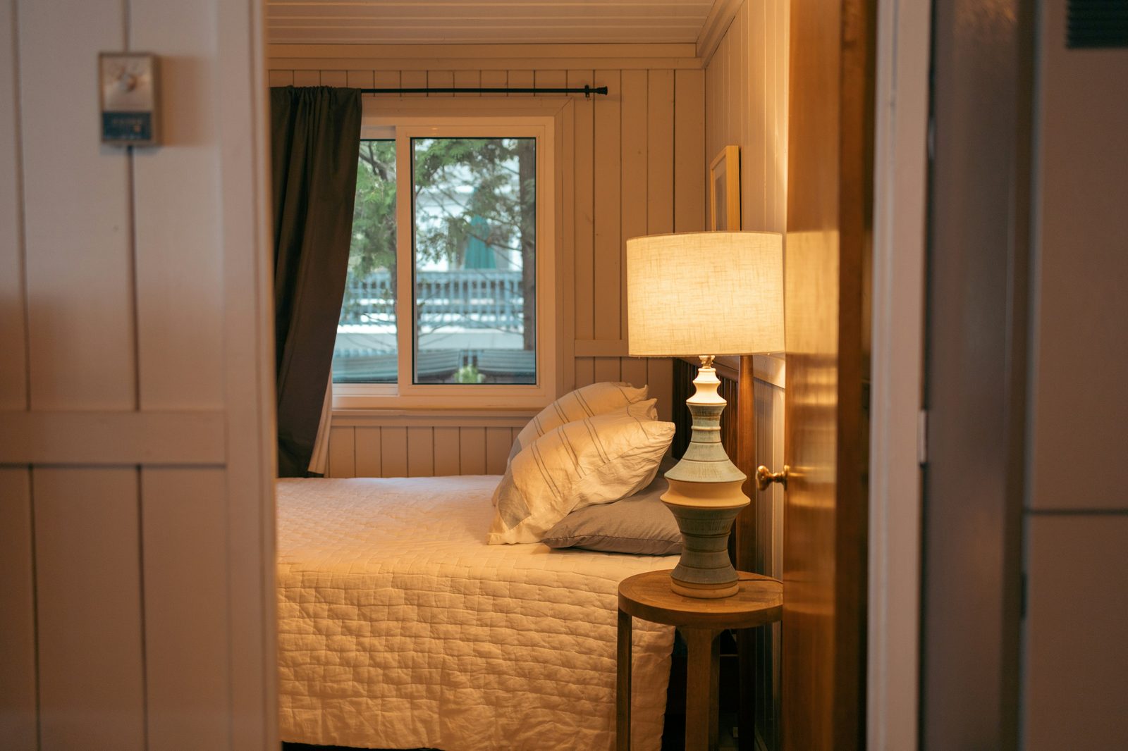 A warmly lit bedroom seen through an open doorway, representing a safe and welcoming home